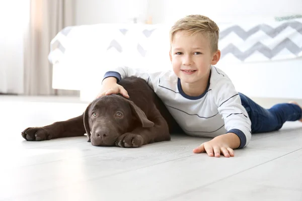 Söt liten pojke med hund på golvet hemma — Stockfoto