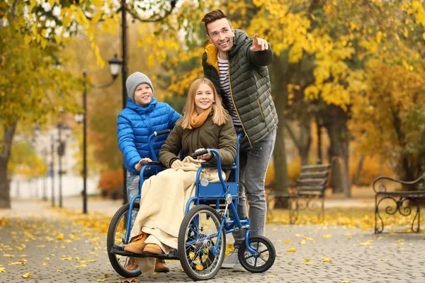 Adolescente en fauteuil roulant avec sa famille à l'extérieur le jour de l'automne — Photo