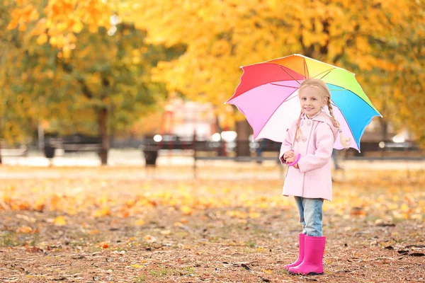 Roztomilá holčička s deštníkem rainbow v podzimním parku — Stock fotografie