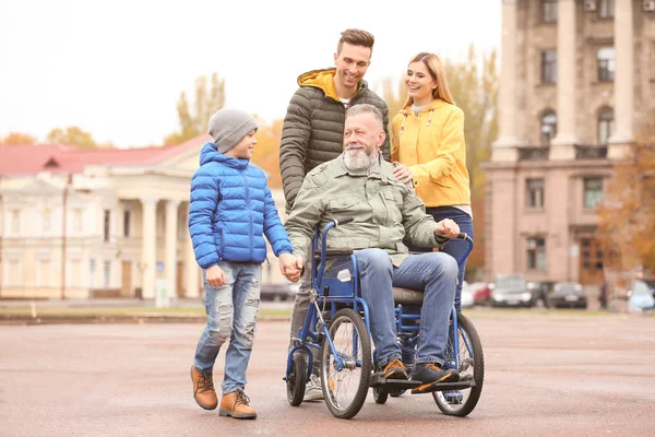 Bejaarde man in rolstoel met zijn gezin buiten op herfstdag — Stockfoto