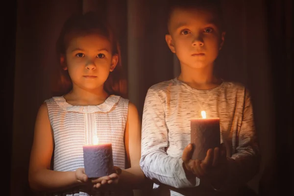 Malé děti drží hořící svíčky v temnotě — Stock fotografie