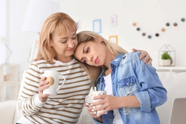 Rijpe vrouw en haar triest dochter drinken koffie thuis — Stockfoto