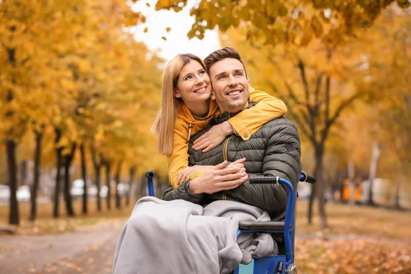 Vrouw met haar man in rolstoel buitenshuis op herfstdag — Stockfoto