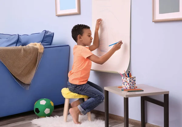 Menino afro-americano desenhando em rolo de papel dentro de casa — Fotografia de Stock