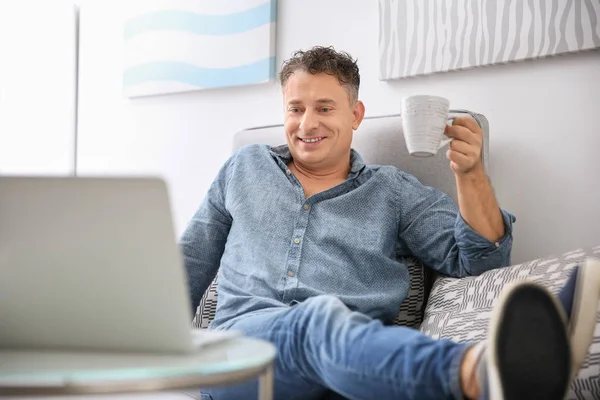 Bello uomo maturo con caffè seduto sul divano a casa — Foto Stock