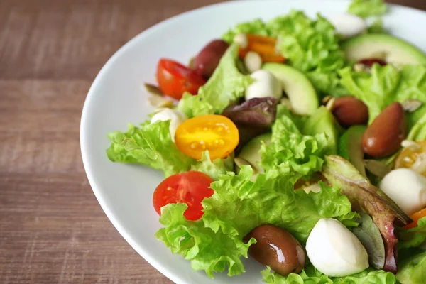 Teller mit leckerem Gemüsesalat auf Holzgrund, Nahaufnahme — Stockfoto