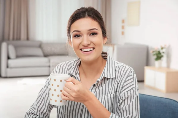 Mujer sonriente en blusa rayada bebiendo té en el interior — Foto de Stock