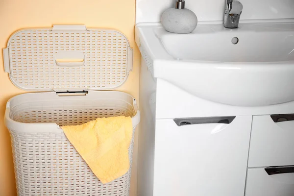 Laundry basket near sink in bathroom — Stock Photo, Image