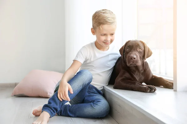 Mignon petit garçon avec chien près de la fenêtre à la maison — Photo