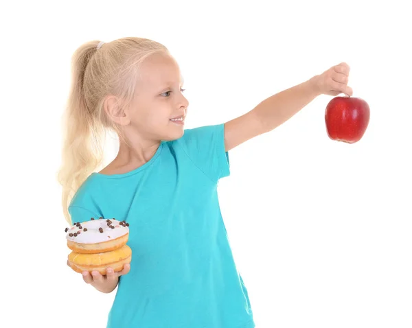 Маленькая девочка со свежим яблоком и сладкими пончиками на белом фоне — стоковое фото