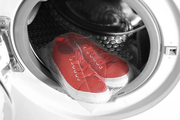 Mesh with red sneakers in washing machine, closeup — Stock Photo, Image