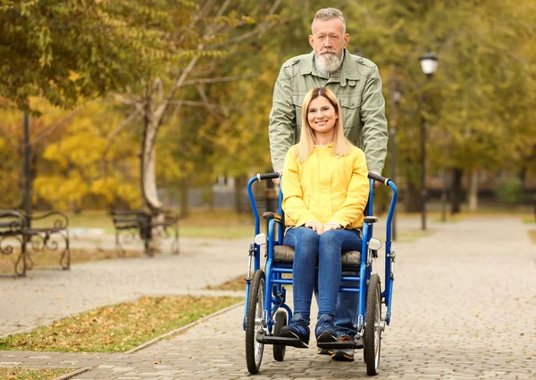 Starszy człowiek z córką na wózku inwalidzkim na zewnątrz na jesienny dzień — Zdjęcie stockowe