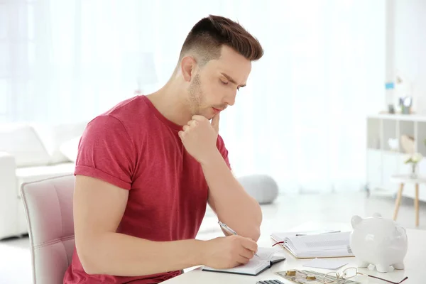 Jovem contando impostos à mesa dentro de casa — Fotografia de Stock