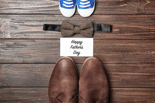 Pajarita, zapatos grandes y pequeños sobre fondo de madera. Composición del día del padre —  Fotos de Stock