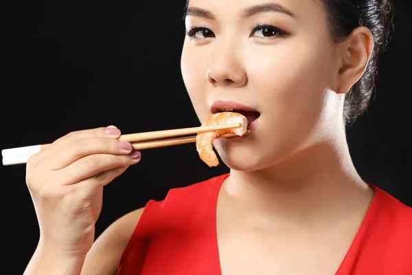 Mooie Aziatische vrouw eten garnalen op zwarte achtergrond — Stockfoto