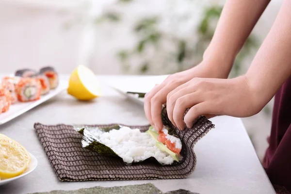 Ung kvinna att göra sushi rullar hemma — Stockfoto