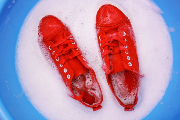 Pair of red sneakers in plastic basin — Stock Photo, Image