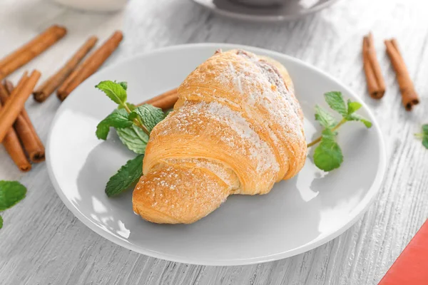 Beyaz ahşap masa üzerinde lezzetli kruvasan ile plaka