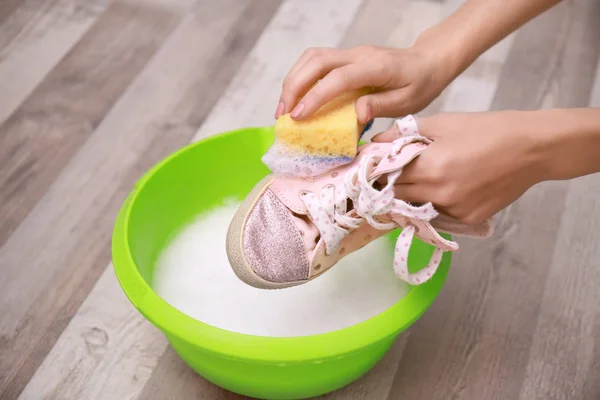 Vrouw wassen sneaker met spons over kunststof bekken, close-up — Stockfoto