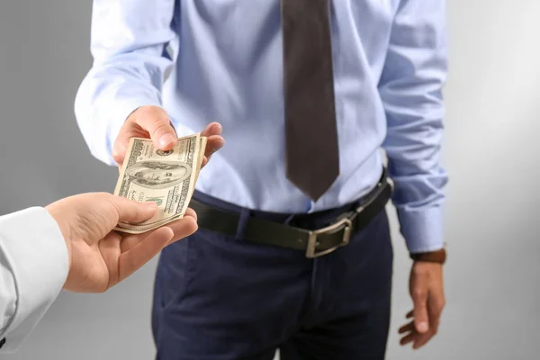 Woman giving money to man on light background — Stock Photo, Image