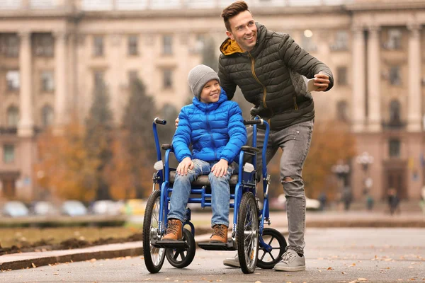 Homme avec son fils en fauteuil roulant prenant selfie à l'extérieur le jour de l'automne — Photo