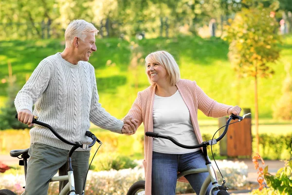 Χαριτωμένο ζευγάρι ηλικιωμένων με ποδήλατα στο πάρκο φθινόπωρο — Φωτογραφία Αρχείου