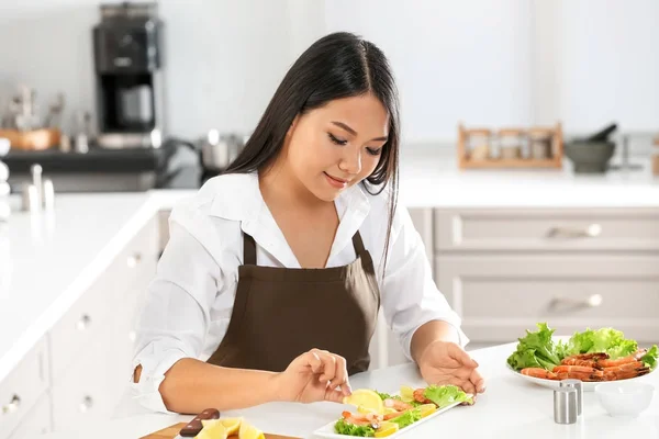 Belle femme asiatique préparant un plat avec des crevettes à table dans la cuisine — Photo