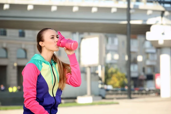 Mujer joven bebiendo batido de proteínas al aire libre — Foto de Stock