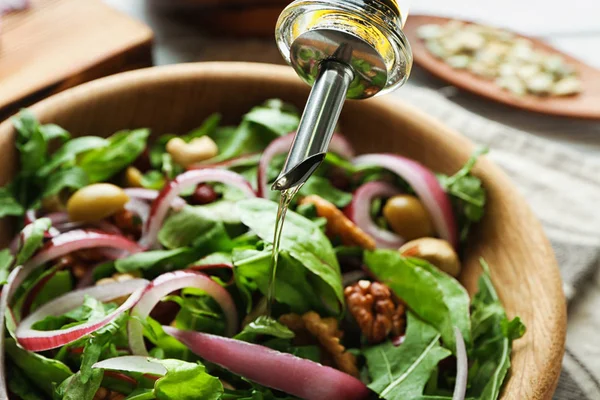 Öl in Schüssel mit leckerem Gemüsesalat gießen, Nahaufnahme — Stockfoto