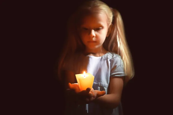 Malá holčička drží hořící svíčku ve tmě — Stock fotografie