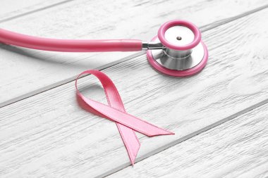 Pembe kurdele ve stetoskop hafif ahşap zemin üzerinde. Meme Kanseri Bilinçlendirme kavramı