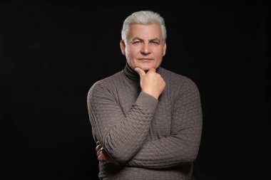 Siyah arka plan üzerine rahat kıyafetler içinde üst düzey yakışıklı