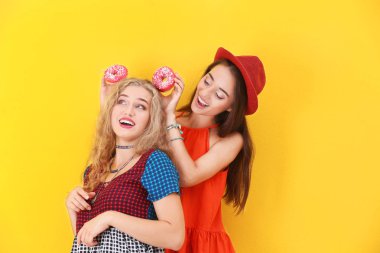 Renk arka plan üzerinde çörek ile poz çekici hipster kızlar