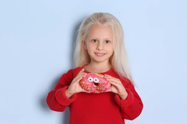 Meisje met zoete donut op kleur achtergrond — Stockfoto