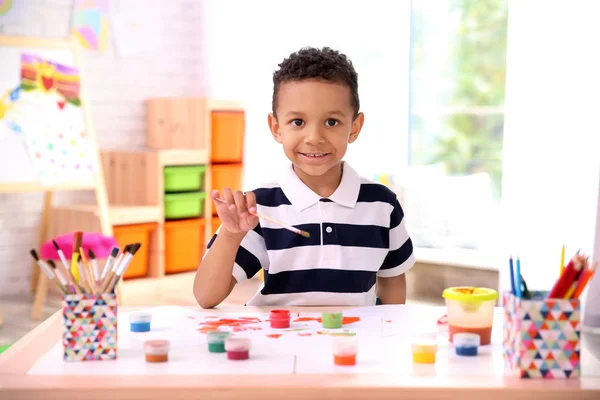 Kleine Afro-Amerikaanse jongen schilderen aan tafel binnenshuis — Stockfoto