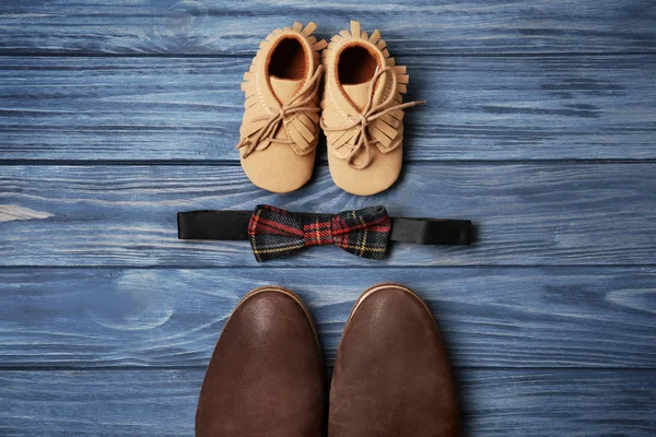 Pajarita, zapatos grandes y pequeños sobre fondo de madera. Composición del día del padre — Foto de Stock