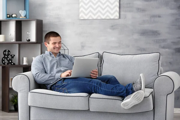 Молодий чоловік з ноутбуком на дивані вдома — стокове фото