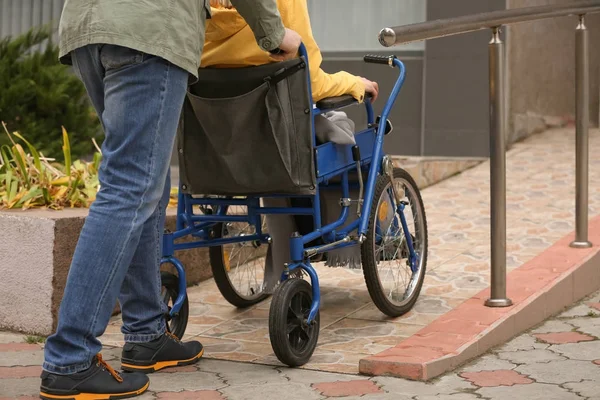 Ο άνθρωπος με τη σύζυγό του σε αναπηρική καρέκλα σε ράμπα σε εξωτερικούς χώρους — Φωτογραφία Αρχείου