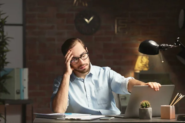 Trött ung man använder laptop i office på natten — Stockfoto