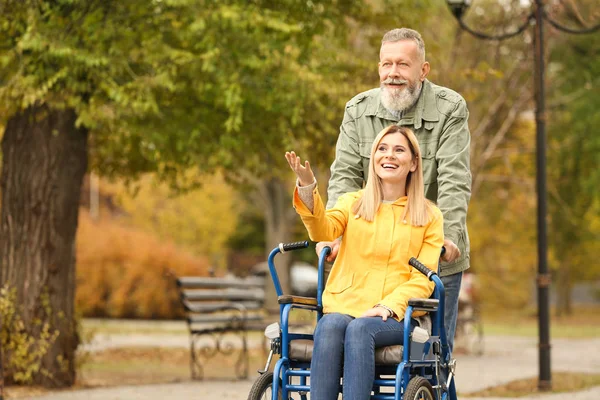 Старший чоловік з дочкою в інвалідному візку на відкритому повітрі в осінній день — стокове фото