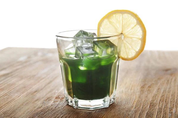 Verre de jus d'herbe de blé avec citron sur table en bois — Photo