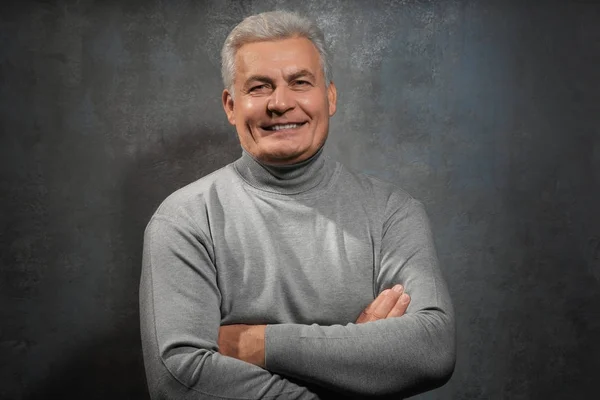 Bonito homem sênior em roupas casuais em fundo cinza — Fotografia de Stock