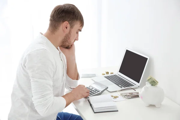 Junger Mann zählt Steuern an Tisch im Haus — Stockfoto