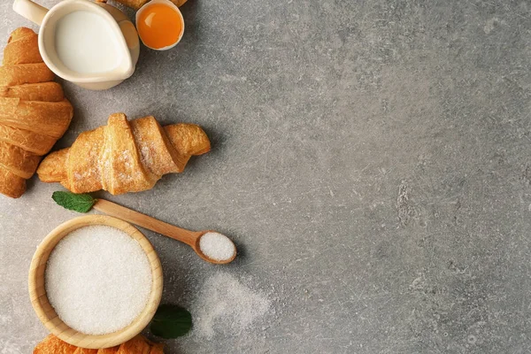 Komposisi dengan croissant lezat dan bahan-bahan pada latar belakang abu-abu — Stok Foto