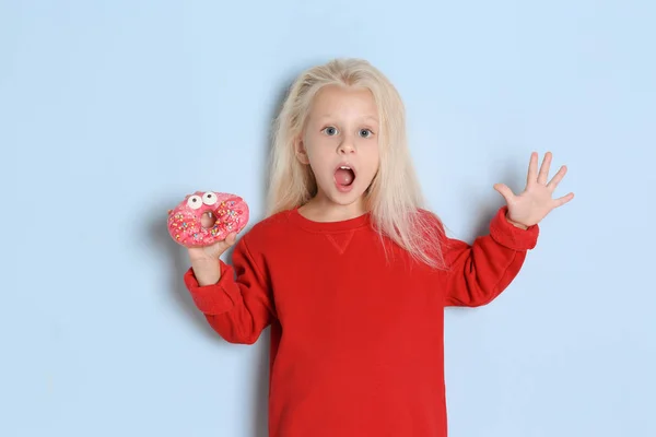 Little girl with sweet donut on color background — Stock Photo, Image