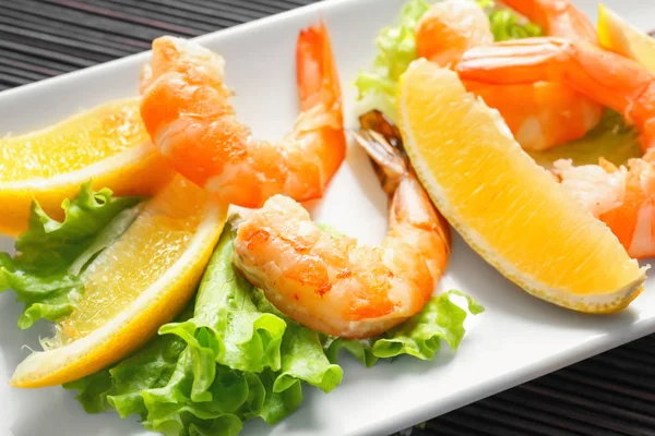 Вкусные креветки с салатом и лимоном на тарелке — стоковое фото