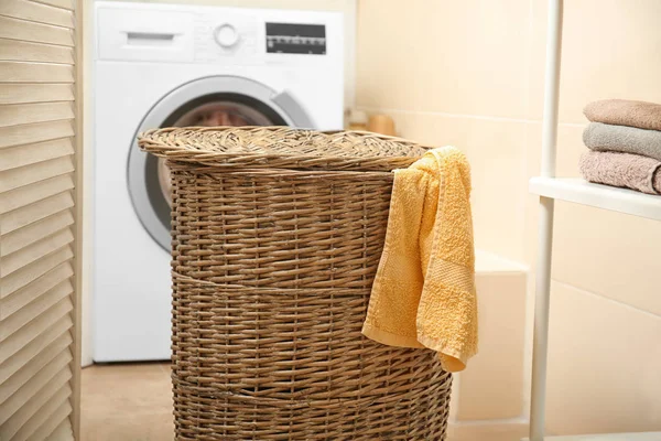 Wicker basket with laundry near washing machine in bathroom — Stock Photo, Image