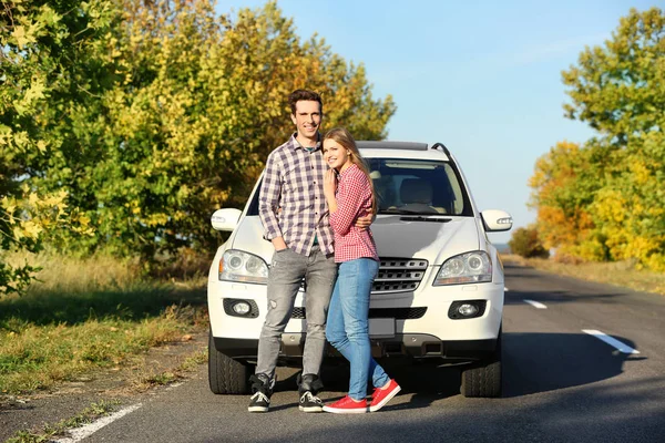 Bonito jovem casal de pé perto do carro ao ar livre — Fotografia de Stock