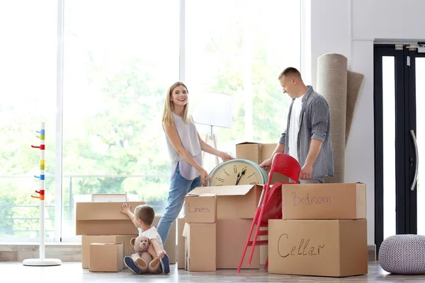 Gelukkige familie uitpakken karton vakken in de kamer in het nieuwe huis — Stockfoto