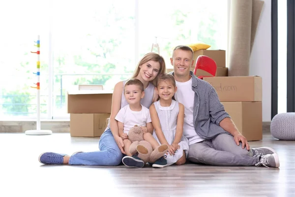 Familia feliz sentada en el piso en la habitación en el nuevo hogar —  Fotos de Stock